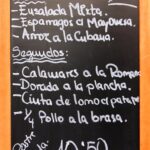 Assiette de poulet grillé posée sur une table de restaurant, avec un menu en arrière-plan