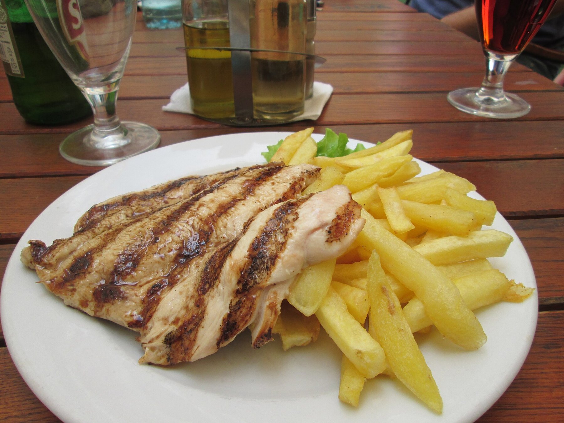 Assiette de poulet grillé posée sur une table de restaurant, avec un menu en arrière-plan