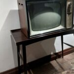 Vieux téléviseur allumé dans un salon, évoquant les dessins animés diffusés le samedi matin
