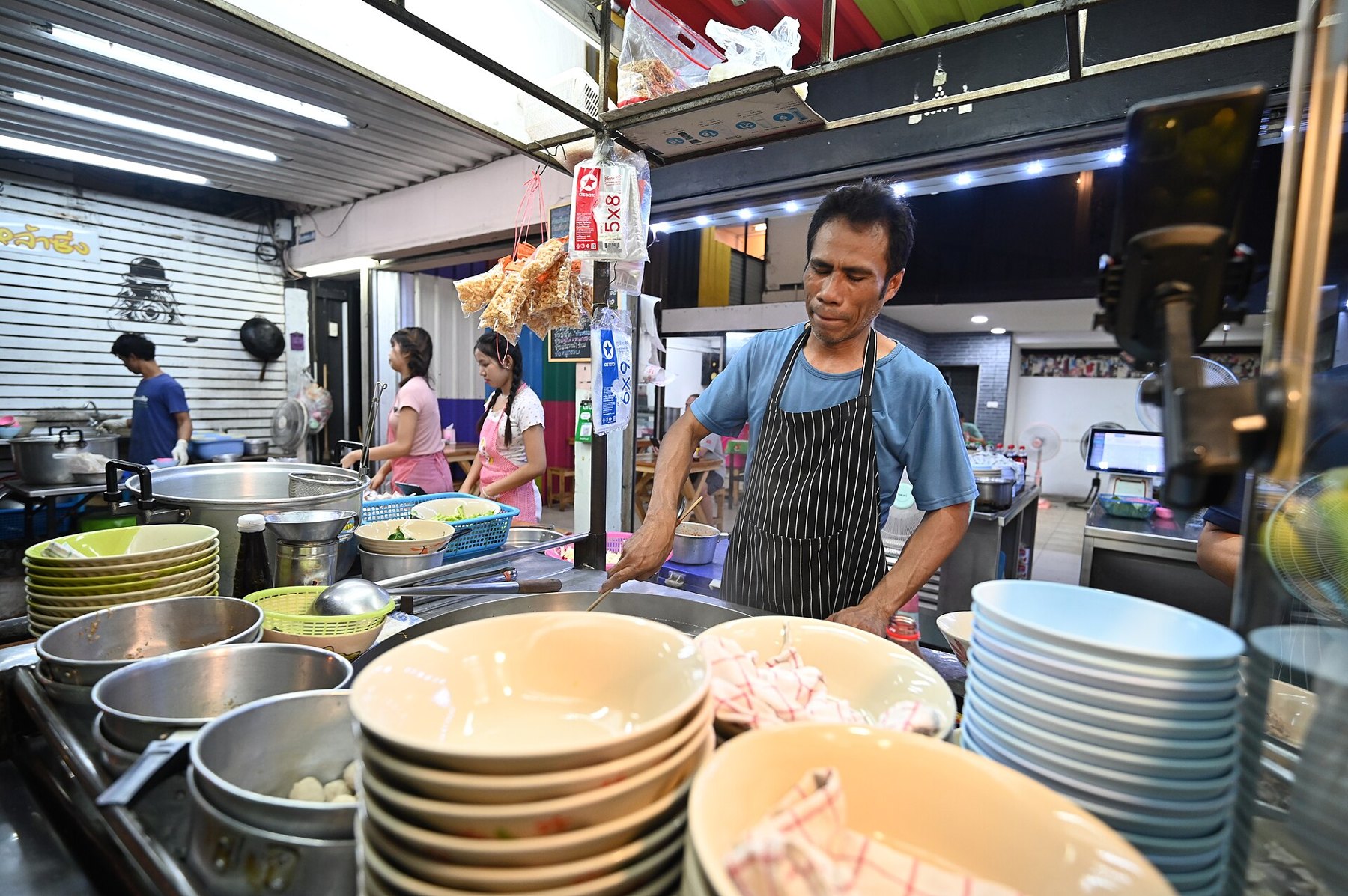 Adolescent assis dans une cuisine éclairée la nuit, à côté d'un réfrigérateur ouvert, dans une ambiance familiale détendue
