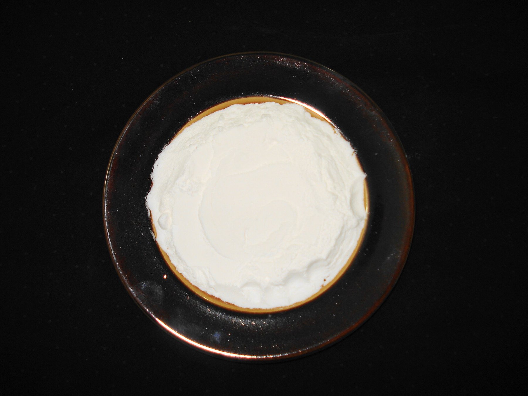 Gâteau raté affaissé sur un plan de travail de cuisine, avec un petit bol de poudre blanche à côté