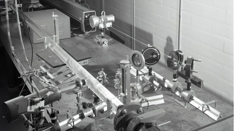 Faisceau laser traversant un laboratoire de physique sombre, illustrant les expériences d'optique quantique