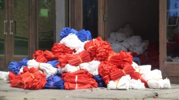 Sacs de courses en tissu réutilisables posés sur une table en bois, à côté de bocaux en verre