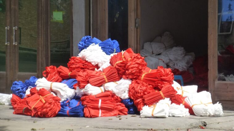 Sacs de courses en tissu réutilisables posés sur une table en bois, à côté de bocaux en verre