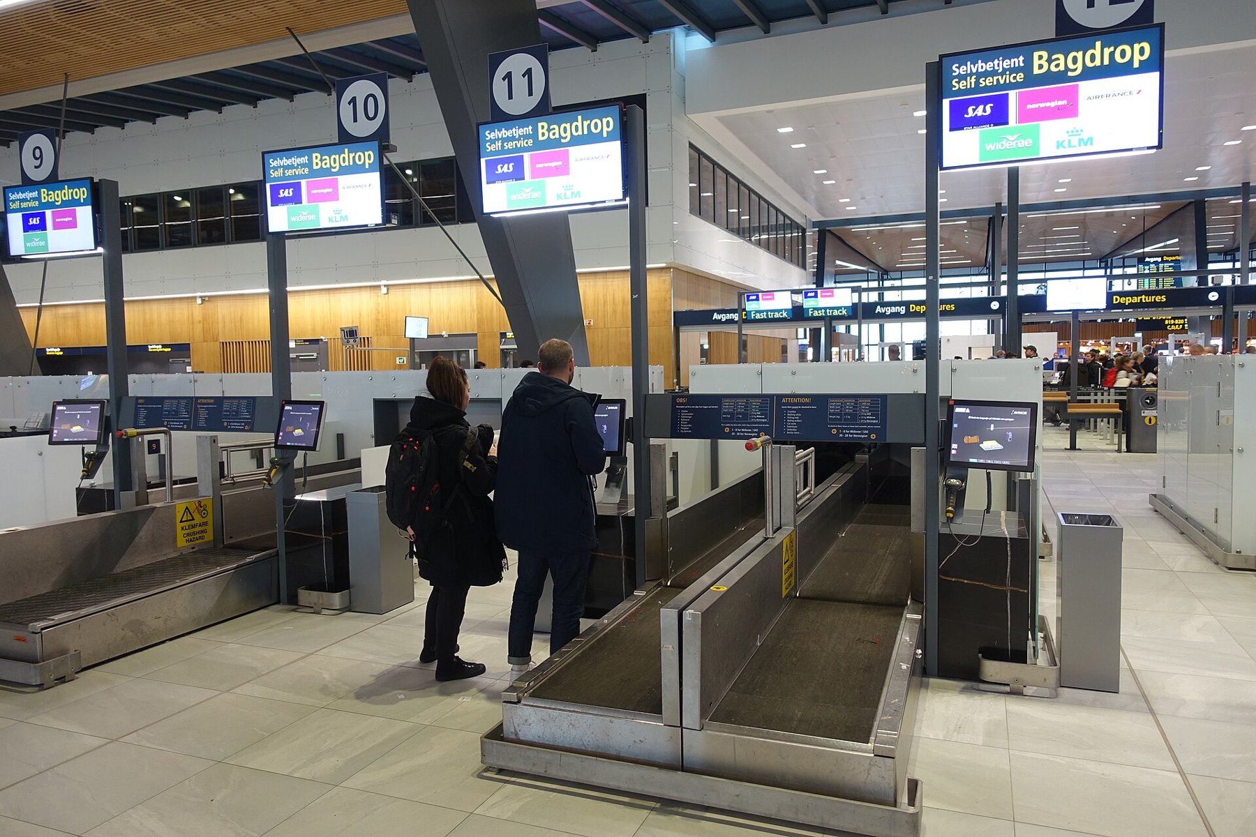 Comptoir d'enregistrement d'un aéroport avec des voyageurs et des valises, illustrant une règle bagages en cabine