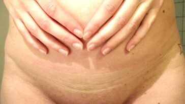 Femme enceinte assise dans un salon lumineux, mains posées doucement sur son ventre