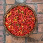 Panier de légumes frais posé sur une table en bois, à côté d'une assiette de viande grillée