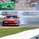 Un SUV électrique blanc en dérive sur un circuit de course, avec un nuage de fumée de pneus